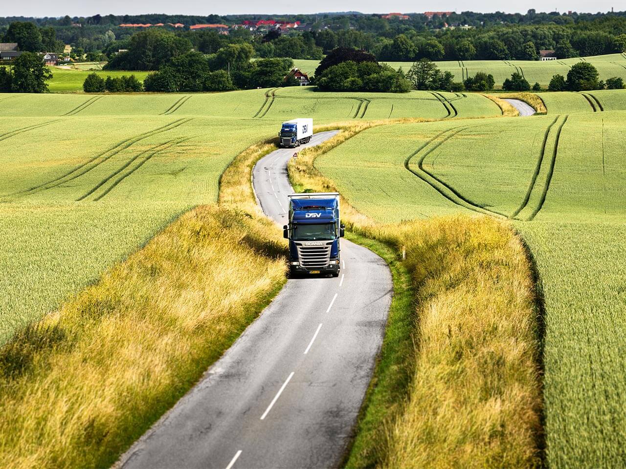 DSV lastbilar som kör genom åkerlandskap